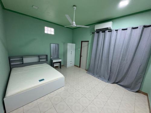 a bedroom with a white bed and green walls at H&F guest house in Maradhoo
