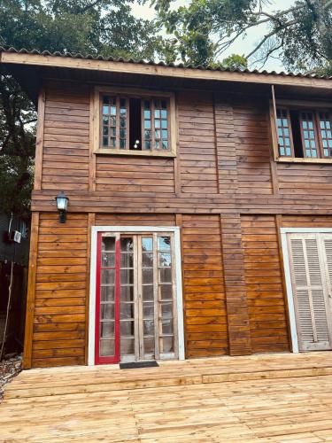 a log cabin with a red door and two windows at Ilha do Mel- Encantadas- Vilarejo Hospedagem in Ilha do Mel