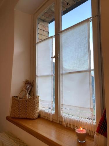 a window with a candle on a wooden window sill at Sot I Volz - Affittacamere in Arta Terme