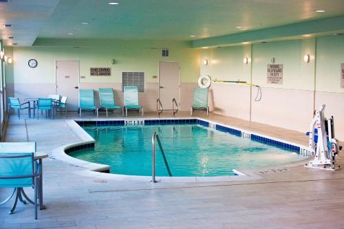 a swimming pool with chairs and a table in a building at SpringHill Suites by Marriott Corpus Christi in Corpus Christi