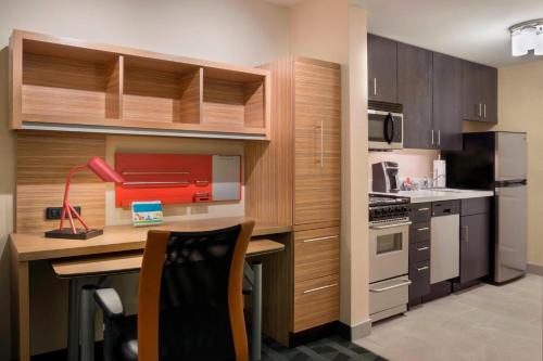 une cuisine avec des placards en bois et un bureau avec une imprimante rouge dans l'établissement TownePlace Suites by Marriott Ottawa Kanata, à Ottawa