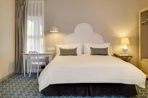 a bedroom with a large white bed and a desk at Protea Hotel by Marriott Cape Town Mowbray in Cape Town