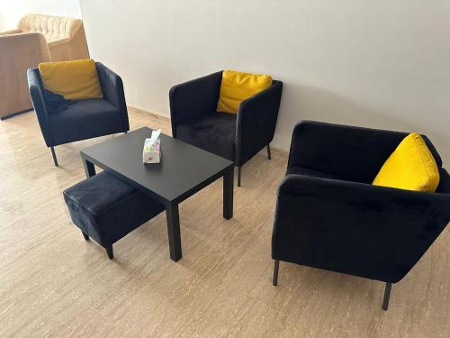three chairs and a table with yellow pillows at Appartement haut standing Mohammedia Parc in Mohammedia