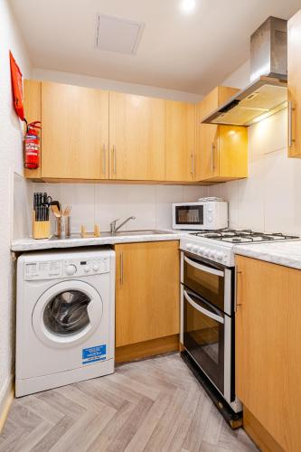 a kitchen with a washing machine and a stove at Newly Furnished Flat 4 Minutes Walk To Metro in Glasgow