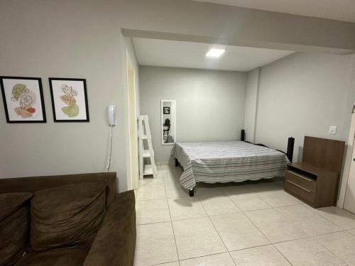 a bedroom with a bed and a couch in it at Studio no coracao do Kobrasol in São José