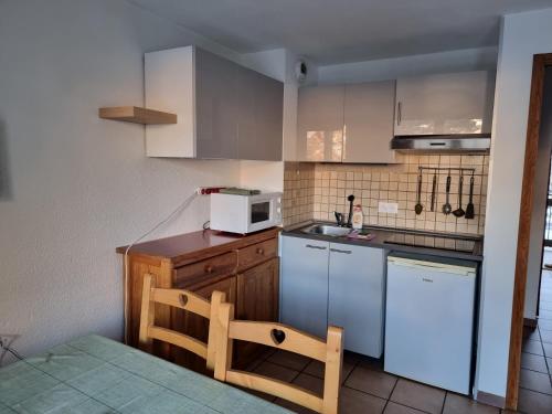 La cuisine est équipée de placards blancs et d'un four micro-ondes blanc. dans l'établissement Signal du Prorel Serre Chevalier Briançon 
