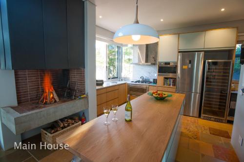 a kitchen with a table with wine glasses and a fireplace at Bokkombaai in Bloubergstrand