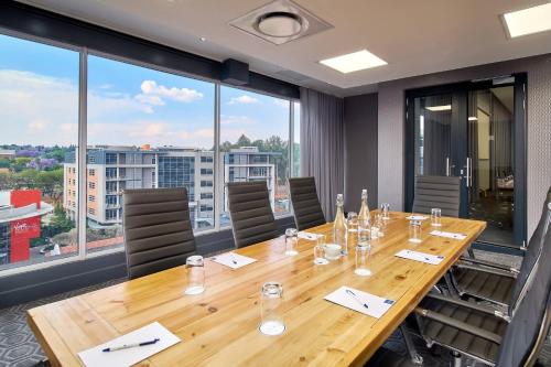 a conference room with a wooden table and large windows at Protea Hotel by Marriott Pretoria Loftus Park in Pretoria