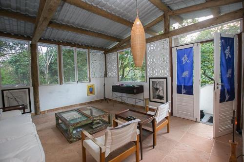 a living room with a table and chairs and windows at Mandacaru Guest House in Praia do Forte