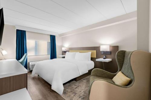 a hotel room with a bed and a chair at Latitude Suites Tinton Falls Eatontown - BW Premier Collection in Tinton Falls