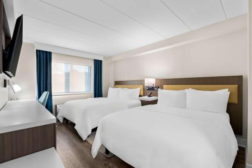 a hotel room with two beds and a window at Latitude Suites Tinton Falls Eatontown - BW Premier Collection in Tinton Falls