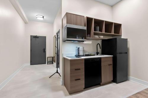 a kitchen with a black refrigerator and a stove at Latitude Suites Tinton Falls Eatontown - BW Premier Collection in Tinton Falls
