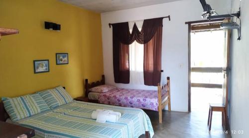 a bedroom with two beds and a window at Pousada Arco-Iries de Itaúnas ES in Conceição da Barra