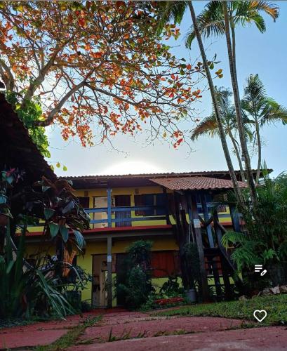 a yellow building with palm trees in front of it at Pousada Arco-Iries de Itaúnas ES in Conceição da Barra