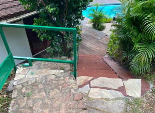 a walkway with a green rail next to a pool at Moorea Happy Bungalow in Teavaro