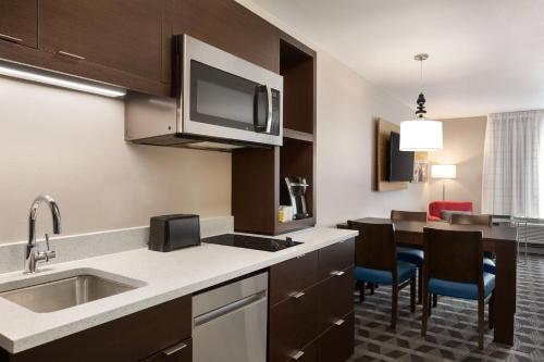 a kitchen with a sink and a table with chairs at TownePlace Suites Cedar Rapids Marion in Cedar Rapids