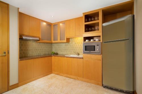 a kitchen with wooden cabinets and a stainless steel refrigerator at JW Marriott Hotel Medan in Medan