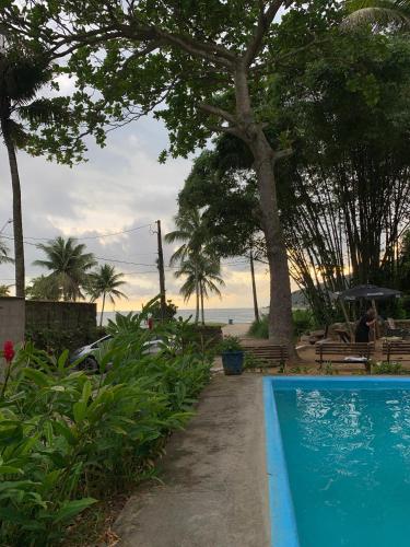 a blue swimming pool next to a beach at Frente ao Mar - Suites com Piscina Aquecida, SPA Privativo, Vista ao Mar ou Montanha, com Estacionamento- Raizes do Mar ECO Hotel in Guarujá