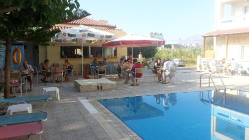 a group of people sitting around a swimming pool at Eleni Palace in Amoudara Herakliou
