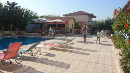a woman and a child standing next to a swimming pool at Eleni Palace in Amoudara Herakliou