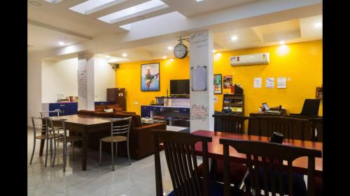 a dining room with yellow walls and tables and chairs at Joey's Hostel Delhi in New Delhi