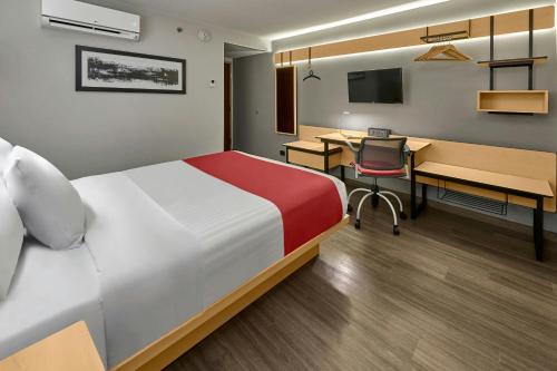a hotel room with a bed and a desk and a computer at City Express by Marriott Queretaro Jurica in Querétaro