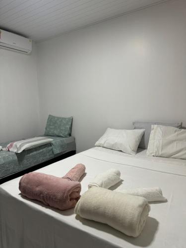 two towels on a table with a bed and a couch at Casa em Condomínio - Salinópolis in Salinópolis