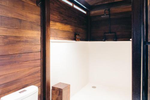 a bathroom with a toilet and a wooden wall at Casa Selva Sayulita in Sayulita