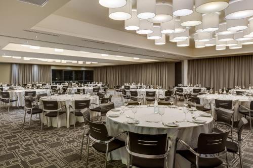a banquet hall with white tables and chairs at Protea Hotel Fire & Ice! by Marriott Pretoria Menlyn in Pretoria