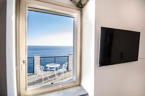 a window with a view of the ocean with a table and chairs at Crêuza de Mä in Riomaggiore