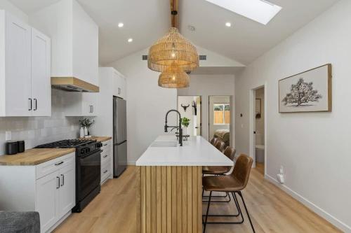 a kitchen with white cabinets and a large island with a sink at The Oaks, Stylish Luxury Stay, Fire Pit & Patio in Thousand Oaks