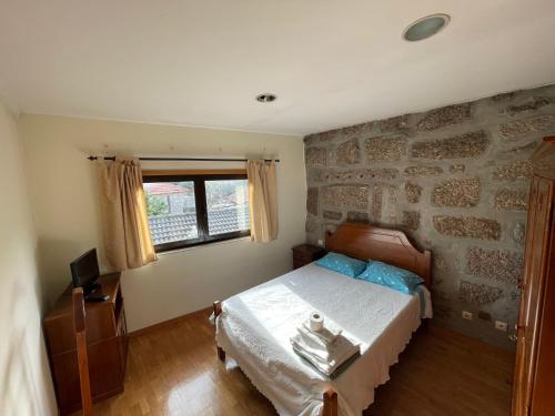 a bedroom with a bed and a stone wall at Quinta do Eirô in Fonte Arcada