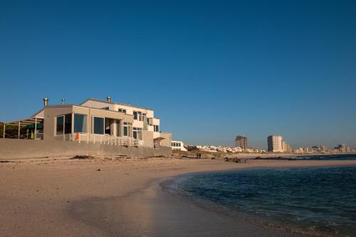 a house on the beach next to the ocean at Bokkombaai in Bloubergstrand