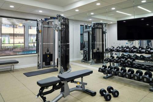 a gym with dumbbells and a flat screen tv at Sheraton Grand Rapids Airport Hotel in Grand Rapids