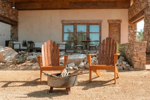 two wooden chairs sitting in front of a house at Hábimo - Valle de Guadalupe in Valle de Guadalupe