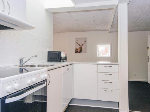 a white kitchen with a sink and a microwave at Charming Retreat in Ringkobing - By Traum Ferienwohnungen in Ringkøbing