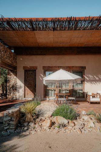 a patio with a table and a white umbrella at Hábimo - Valle de Guadalupe in Valle de Guadalupe