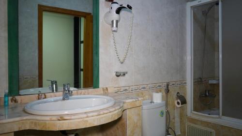 a bathroom with a sink and a mirror at Hôtel Prestige in Nouadhibou