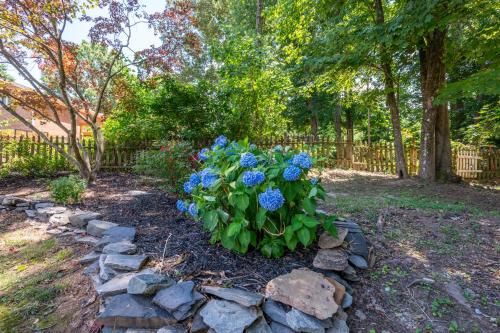 a garden with blue flowers and a stone wall at Arcade, Ping Pong, Hot Tub, Gas Grill, & King Bed in Kernersville