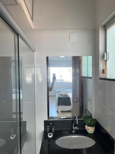 a bathroom with a sink and a mirror and a bedroom at Capitólio Home Suítes in Capitólio