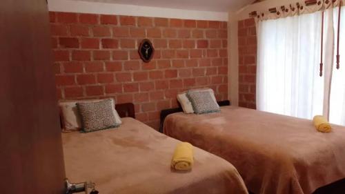 two beds in a room with a brick wall at Villa Marina in Pasto