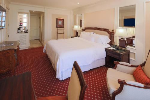 a hotel room with a large white bed and chairs at The Westin Camino Real, Guatemala in Guatemala