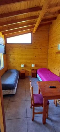 una camera con due letti e un tavolo in una cabina di Depto Castillo a El Bolsón
