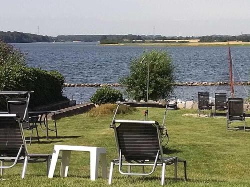 a group of chairs and a table in front of a lake at Holidayapartment4withstudioSchleiblick in Maasholm