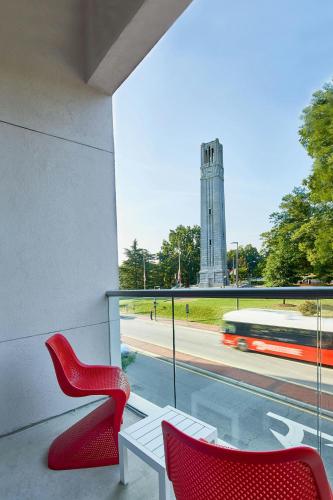 two red chairs and a white table and a bus at Aloft Raleigh in Raleigh