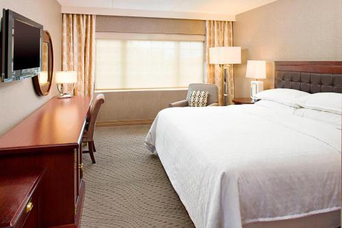 a hotel room with a large bed and a television at Sheraton Rockville Hotel in Rockville