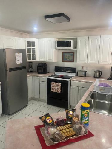a kitchen with white cabinets and appliances with food on the counter at HCEAS villa is 5 min fr. airport & to the beaches in Bon Accord