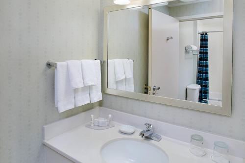a bathroom with a sink and a mirror and towels at SpringHill Suites Manchester-Boston Regional Airport in Manchester