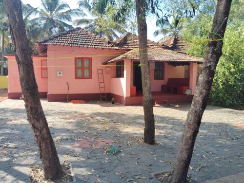 a pink house with palm trees in front of it at Village Oasis Retreat in Haldipur