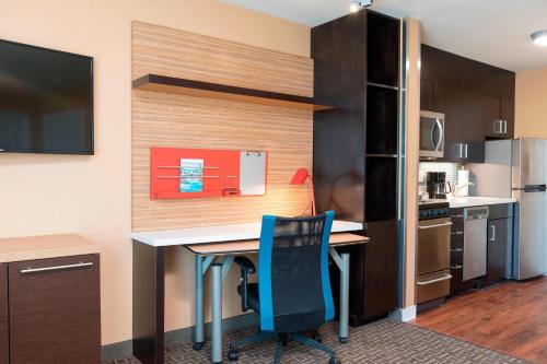 a small kitchen with a desk and blue chairs in a room at TownePlace Suites by Marriott Ontario-Mansfield in Mansfield